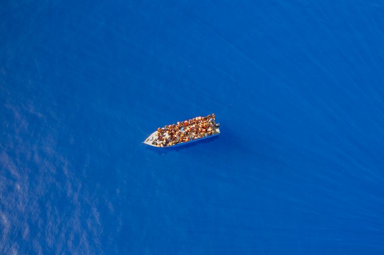 FILE - A group thought to be migrants from Tunisia on board a precarious wooden boat waits to be assisted by a team of the Spanish NGO Open Arms, around 20 miles southwest from the Italian island of Lampedus