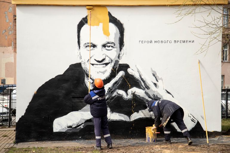 Municipal workers paint over a mural of Navalny in St Petersburg