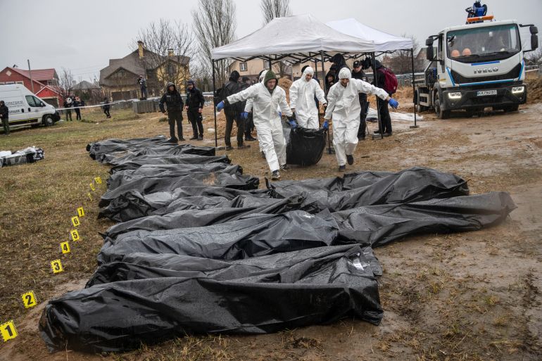 Forensic workers carry the corpse of a civilian killed during the war against Russia after collecting it from a mass grave in Kyiv, Ukraine