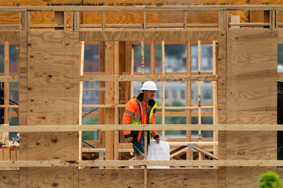 A worker with plans checks construction of a four-story, 45-unit condominium building in Portland, Maine, US