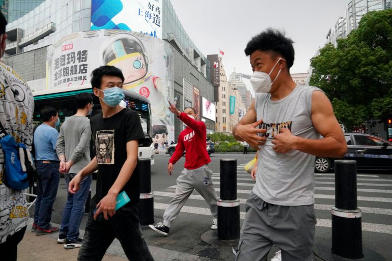 Residents wearing masks walk through a retail street, Wednesday, June 1, 2022, in Shanghai. Traffic, pedestrians and joggers reappeared on the streets of Shanghai on Wednesday as China's largest city began returning to normalcy amid the easing of a strict two-month COVID-19 lockdown that has drawn unusual protests over its heavy-handed implementation. (AP Photo/Ng Han Guan)