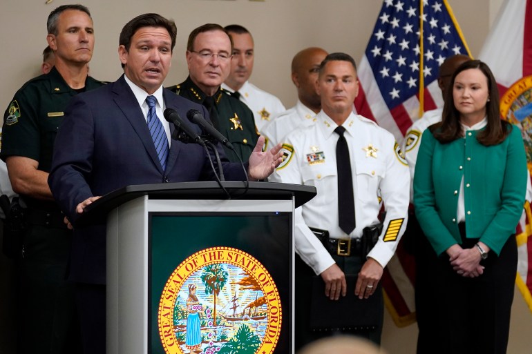 DeSantis at a press conference, surrounded by law enforcement and officials