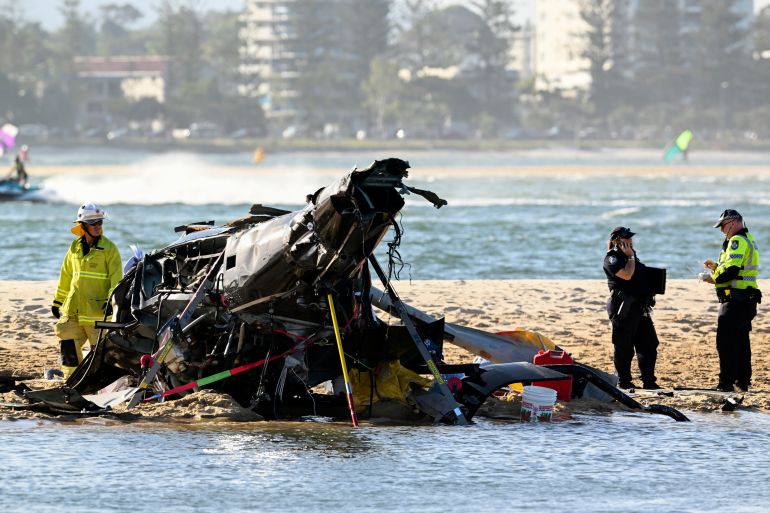 Emergency workers inspect a helicopter at a scene collision near Seaworld, on the Gold Coast, Australia