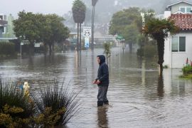 A man wades through a flooded California neighbourhood.