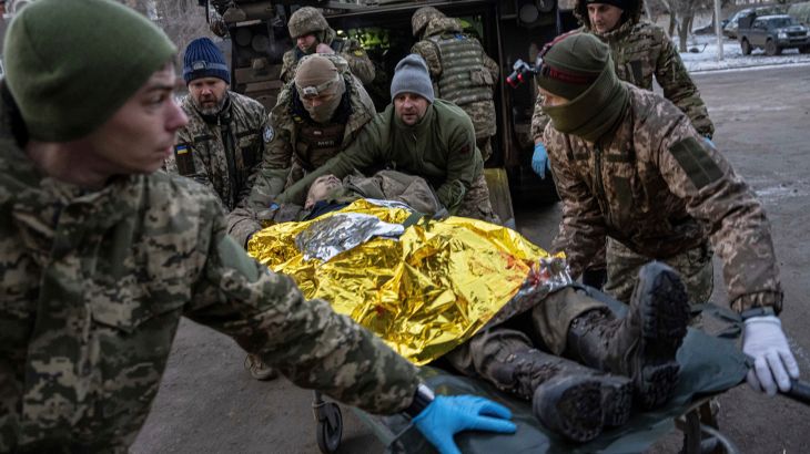 Ukrainian military medics carry an injured serviceman evacuated from the battlefield into a hospital in Donetsk region