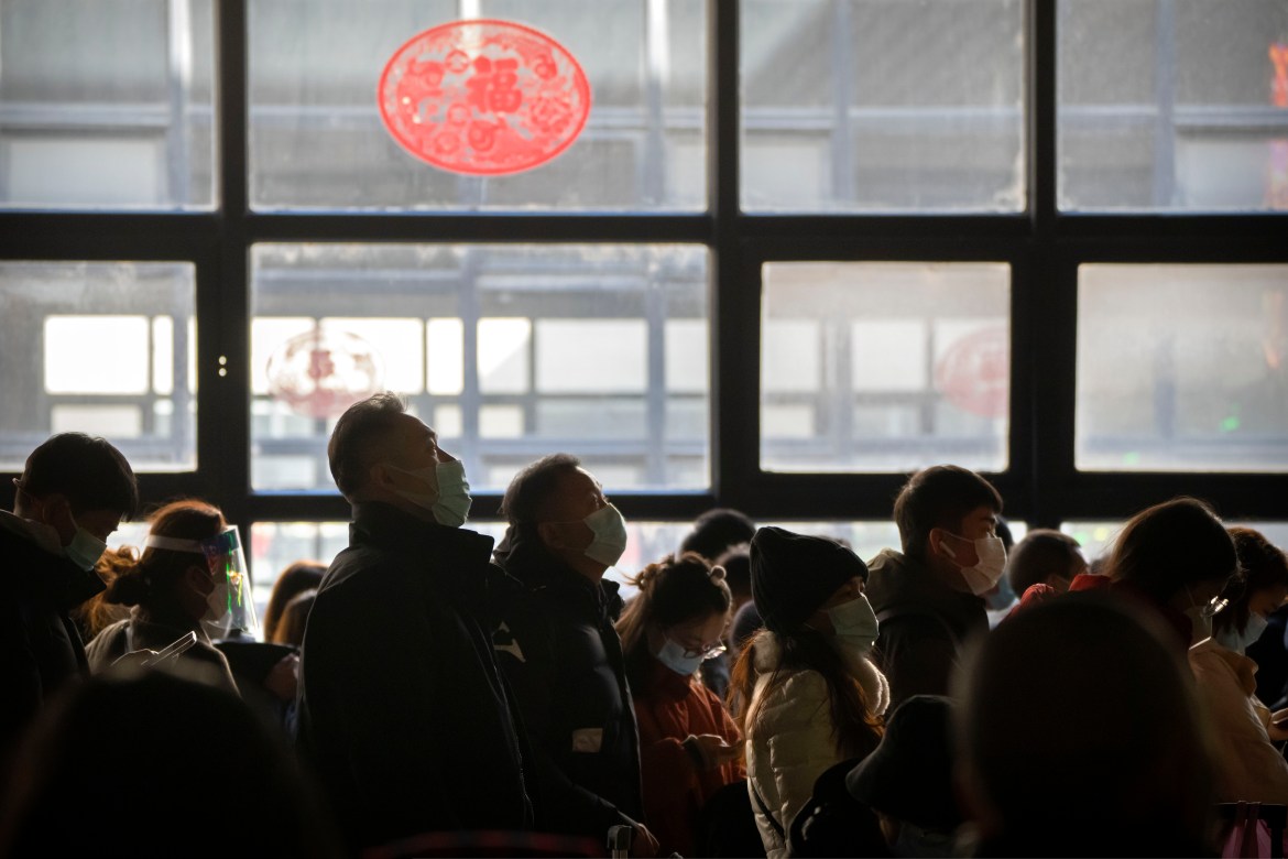 Travelers stand in line to board a train at Beijing West Railway Station in Beijing