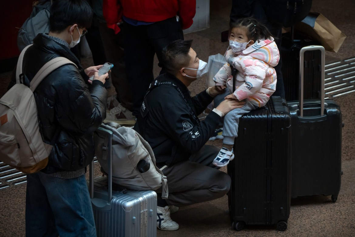 A child sits on a suitcase at Beijing West Railway Station in Beijing