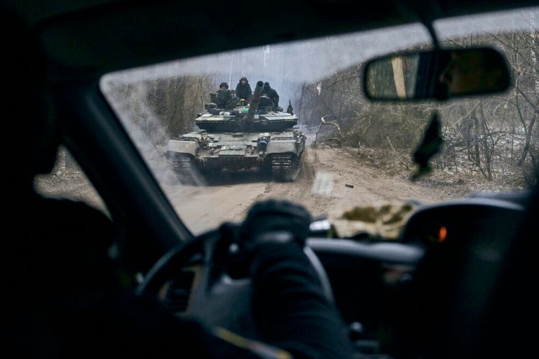 A Ukrainian tank with soldiers is seen through a car window close to the frontline near Kremenna in the Luhansk region, Ukraine, Sunday, Jan. 15, 2023. (AP Photo/LIBKOS)