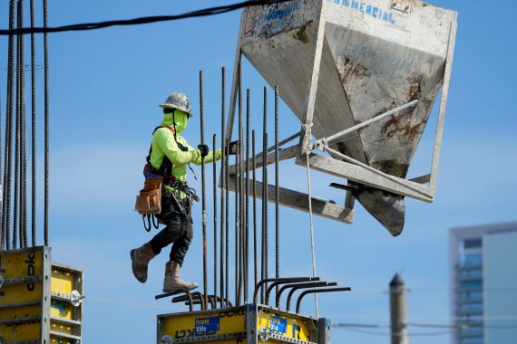 A worker guides a bin into position at a construction site, Tuesday, in Miami, Florida, US
