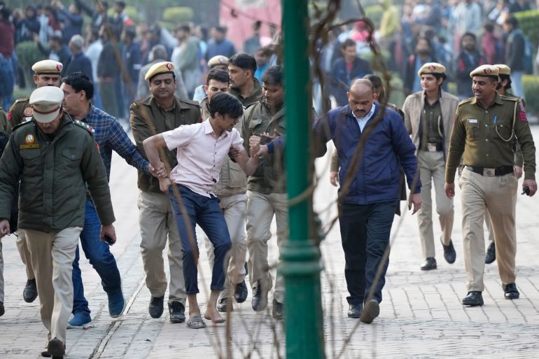 Policemen and security guards of Delhi University escort a protesting student out