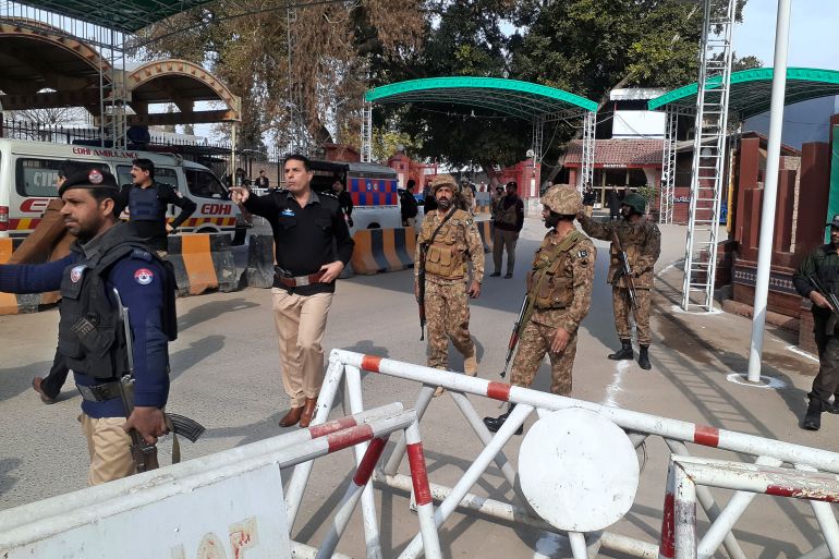 Army soldiers and police officers clear the way for ambulances rushing toward a bomb explosion site, at the main entry gate of police offices, in Peshawar, Pakistan