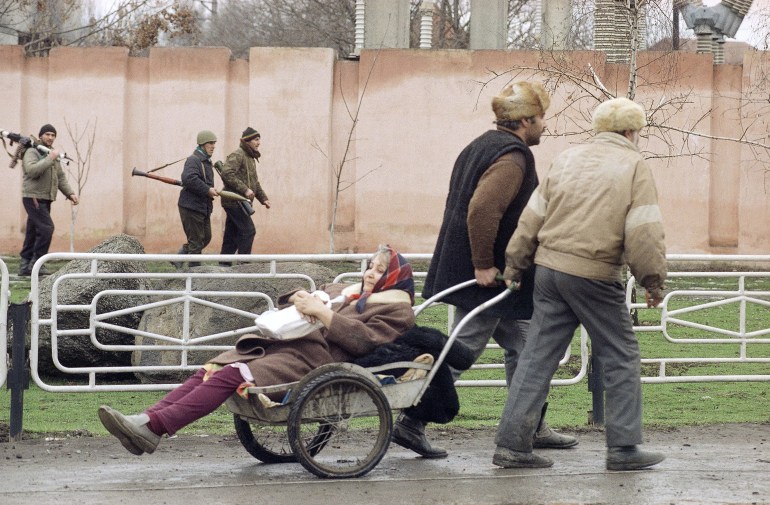 Chechens wheel an elderly woman in a cart away from the fighting in central Grozny on January 8, 1995