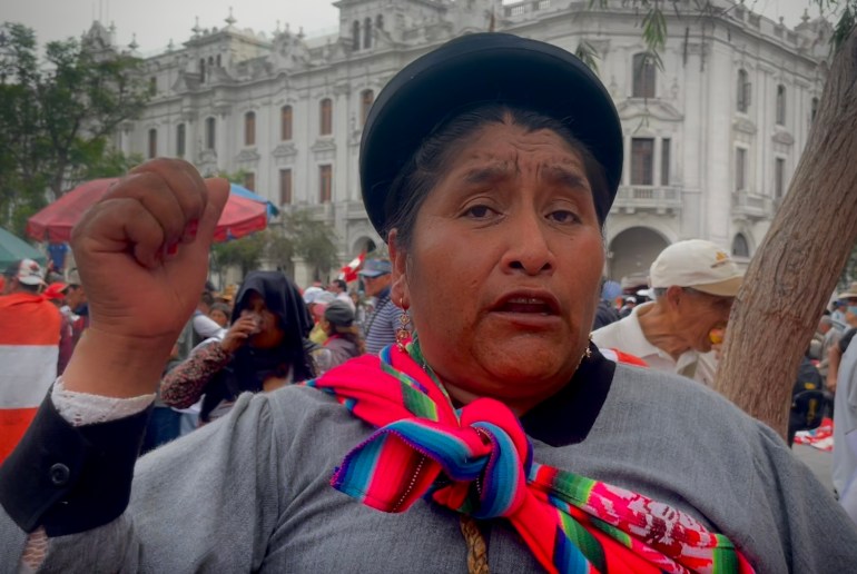 Een demonstrant in Lima kijkt naar de camera en steekt uit protest zijn vuist op.