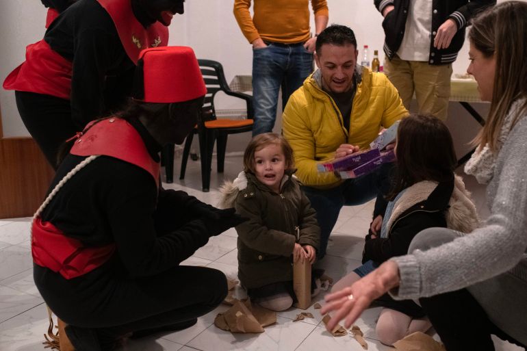 Children from the Mas and Valdés families open Christmas presents