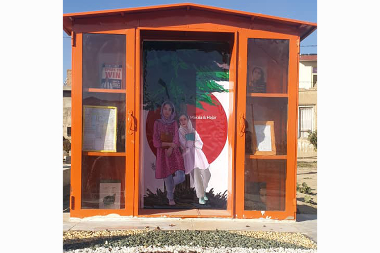 A photo of a small building with a drawing of two girls on it.