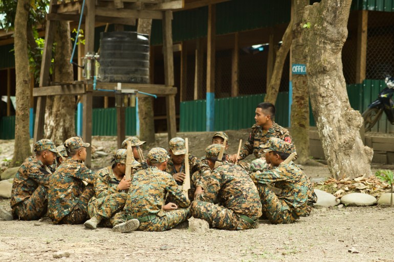 Des soldats des CNF sont assis en cercle sur le sol à l'extérieur du camp Victoria avant l'attaque