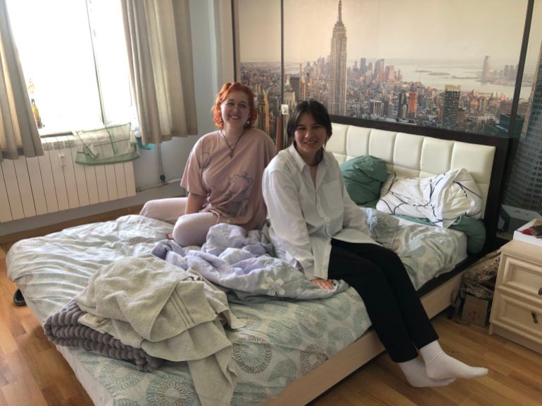 A photo of Tanya and Veronika sitting on their bed.