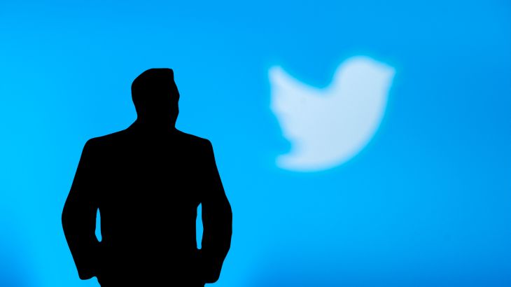 A silhouette of Elon Musk in front of the Twitter logo