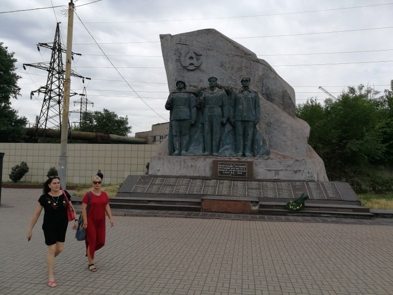 Twee-vrouwen-lopen-langs-een-monument-voor-WWII-helden-in-Mariupol-Oekraïne-in-2019.j
