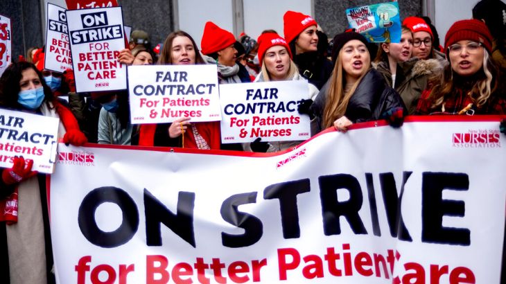 A picket line of nurses hold a sign reading 'on strike'