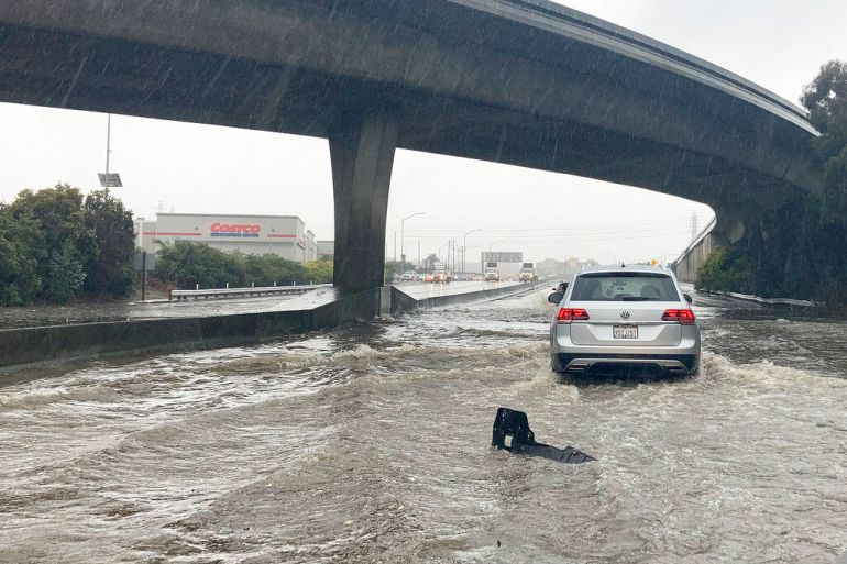 A car tries to drive through a flooded section of a highway