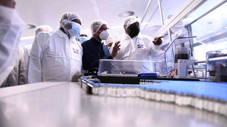 Three men examine a vaccine manufacturing facility in South Africa.