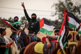 Palestinians waving their national flags take part on horseback in a rally on the 74th anniversary of the Nakba at the border east of Gaza City on May 21, 2022