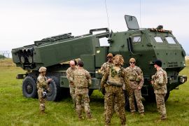 Military personnel stand in front of a High Mobility Artillery Rocket Systems (HIMARS) during the military exercise Namejs 2022 on September 26, 2022, in Skede, Latvia [File: Gints Ivuskans/AFP]