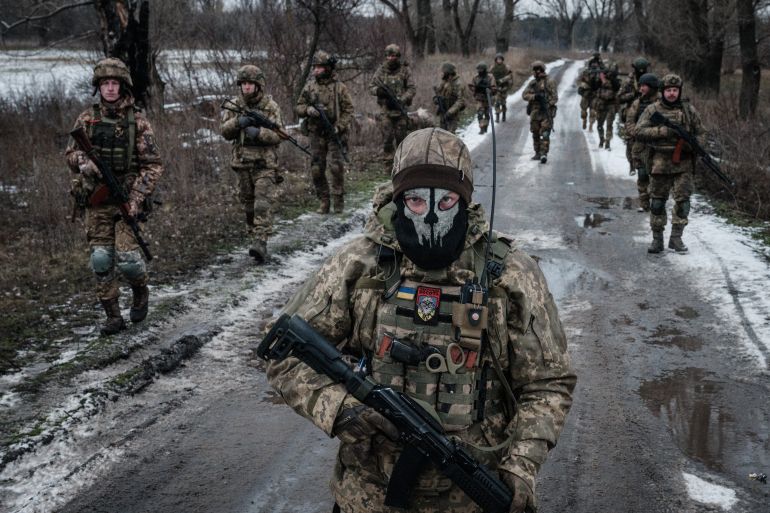 A dozen Ukrainian service members walk on the road towards their base near the front line in the Donetsk region, Ukraine.