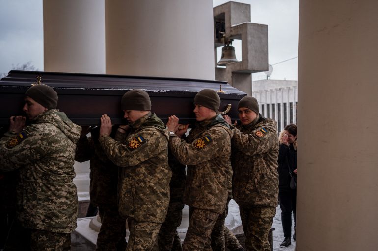 Ukrainian soldiers carry the coffin of Eduard Strauss, a Ukrainian serviceman killed in combat in Bakhmut, during his funeral at the Roman Catholic Parish of Saint Alexanders in Kyiv on February 6, 2023, amid the Russian invasion of Ukraine. (Photo by Dimitar DILKOFF / AFP)