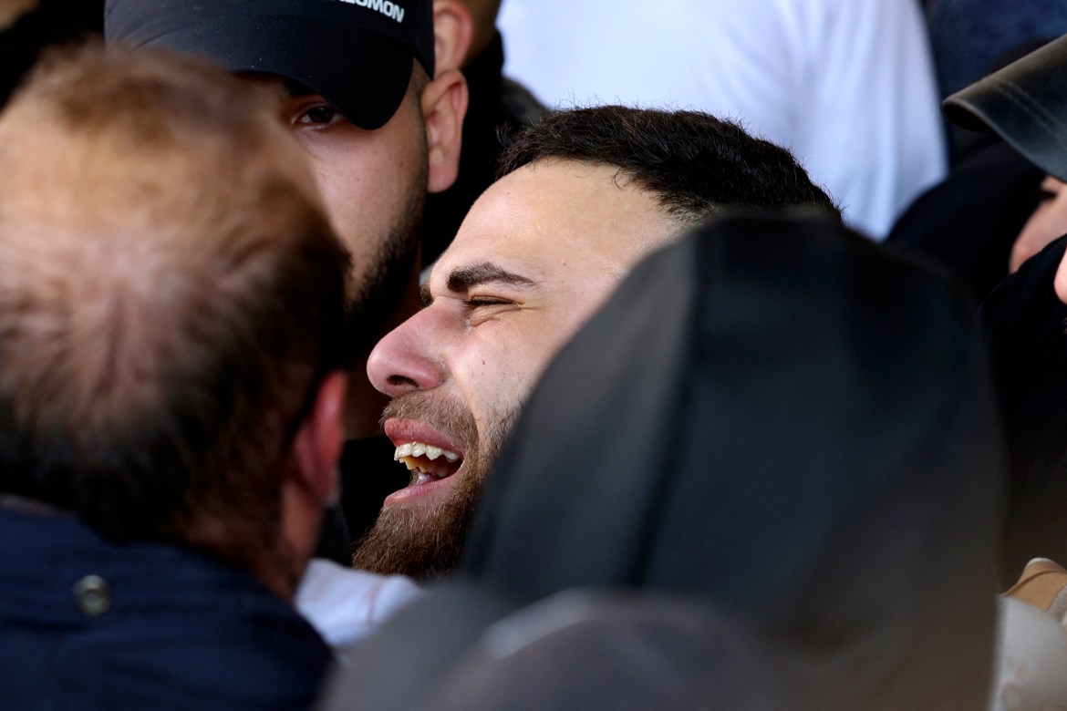 A man weeps as mourners carry the body of a Palestinian from a hospital morgue