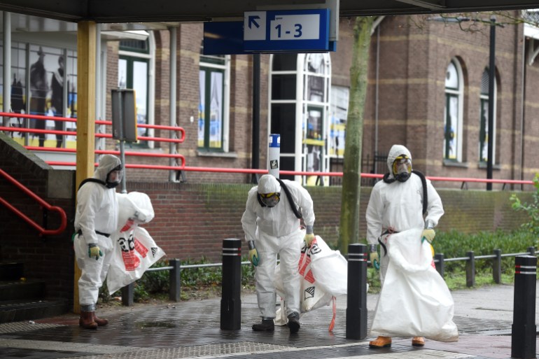 Three cleaners in protective gear outside a train station in the Netherlands