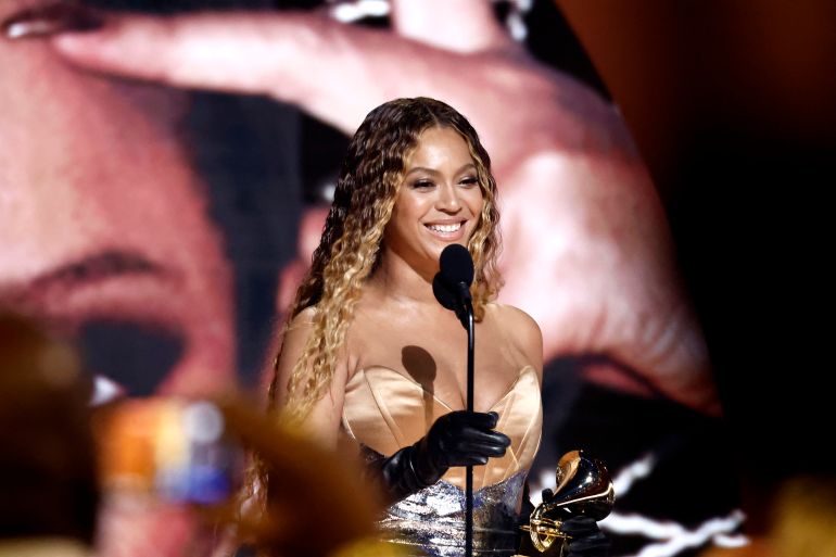 Beyonce smiles as she collects the Grammy for Dest Dance/Electronic Music Album for Renaissance.She is wearing a beige silk evening dress and her hair is in loose waves
