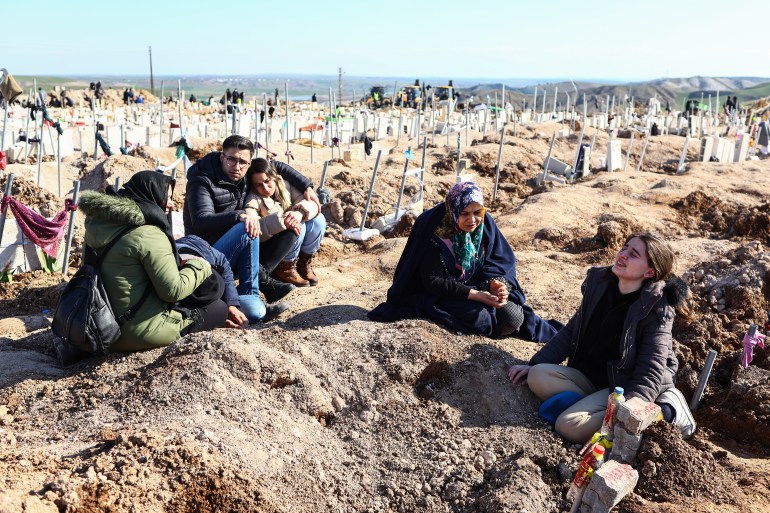 People mourn their relatives at a mass grave site following a major earthquake in Adiyaman, southeast Turkey, February 11, 2023. More than 24,000 people have died and thousands have been injured after two major earthquakes hit southern Turkey and northern Syria on February 6.  Authorities fear the death toll will continue to rise as rescuers search for survivors across the region. 