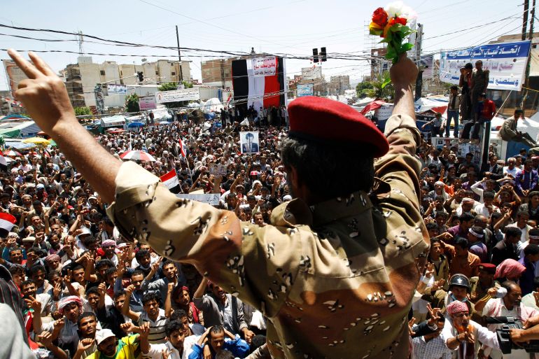 A Republican Guard soldier flashes a victory sign and waves flowers as he declares his defection