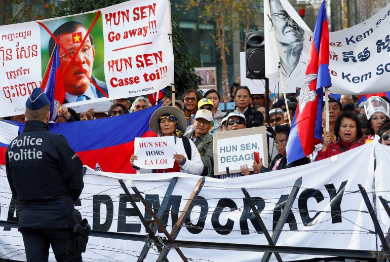 Protesters hold signs saying 'HUN SEN Go away!!!" and others of his face with a red cross over it