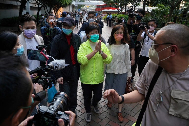 L'ancienne législatrice Helena Wong Pik-wan comparaît devant le tribunal après le rejet d'un appel de l'accusation contre sa libération sous caution.  Elle porte un t-shirt vert citron et a les mains jointes en signe de remerciement.  Elle est accompagnée d'une autre femme.  Les médias sont autour d'elle.