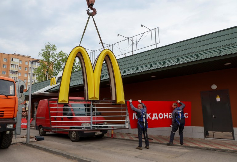 A McDonald's famous golden-arch sign being taken down by workers.