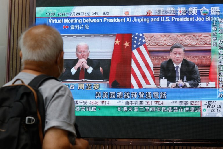 A man watches a monitor showing Biden and Xi in a virtual meeting.