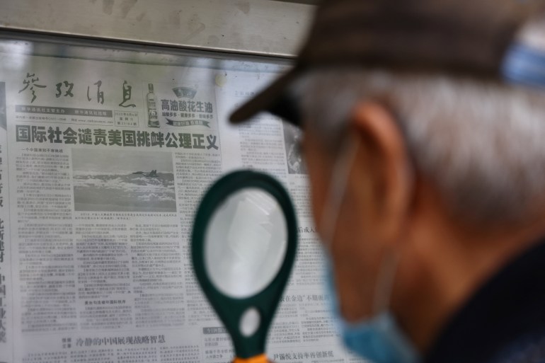 A man reads a newspaper report with an image of military exercises near Taiwan by the Chinese People's Liberation Army's (PLA) Eastern Theatre Command, at a newspaper stand in Beijing, China, August 8, 2022. REUTERS/Tingshu Wang