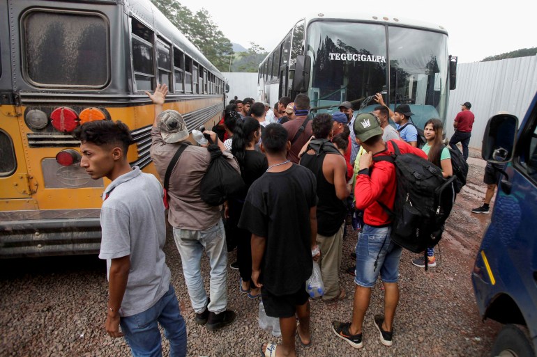 Crowds of migrants and asylum-seekers squeeze between two parked busses