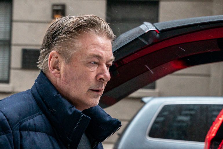 Actor Alec Baldwin leaves his home, with a vehicle seen in the background. He looks stressed.