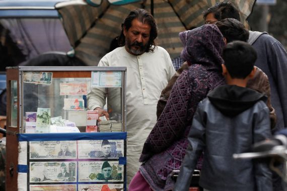 FILE PHOTO: A currency broker stands near his booth, which is decorated with pictures of currency notes, while dealing with customers, along a road in Karachi, Pakistan January 27, 2023. REUTERS/Akhtar Soomro/File Photo