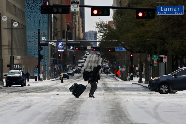 A pedestrian walks across an icy road in Dallas, Texas