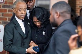 RowVaughn Wells and Al Sharpton holds Nichols's mother's hand as she leans forward with her head down, weeping