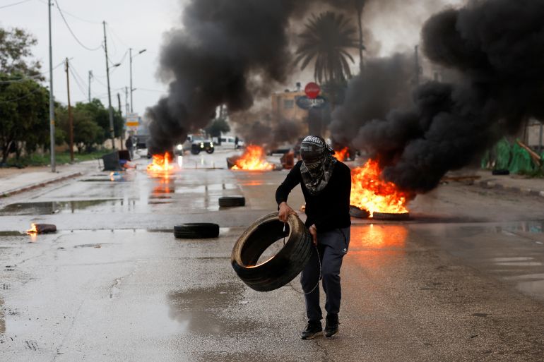 A Palestinian man carries a tyre during clashes with Israeli troops during a military raid in Jericho.