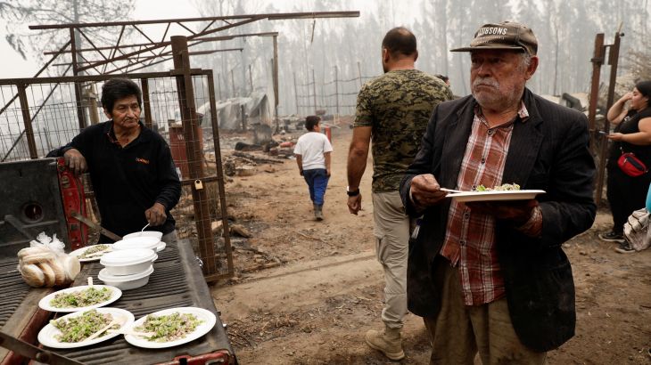 Residents eat after a wildfire burned areas in Santa Juana, Chile