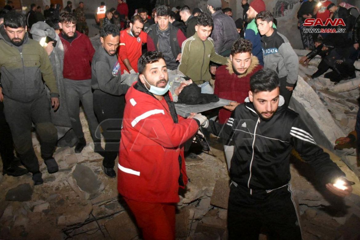 Rescuers carry a person on a stretcher work at the site of a collapsed building, following an earthquake, in Hama, Syria