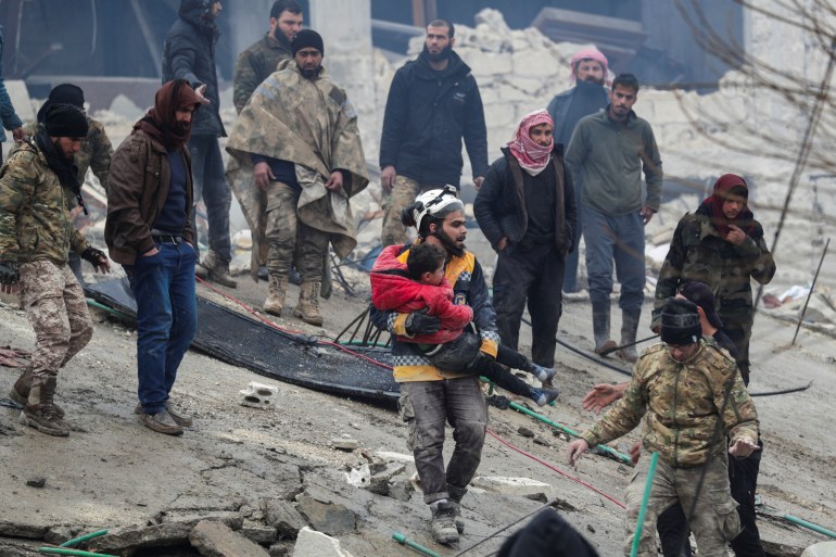 A rescuer carries a child, following an earthquake, in rebel-held town of Jandaris, Syria February 6, 2023.