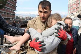 Muhammet Ruzgar, 5, is carried out by a rescuer from the site of a damaged building in Hatay [Umit Bektas/Reuters]